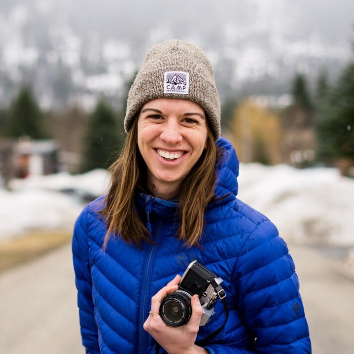 Smiling woman wearing toque and blue puffer jacket holding camera