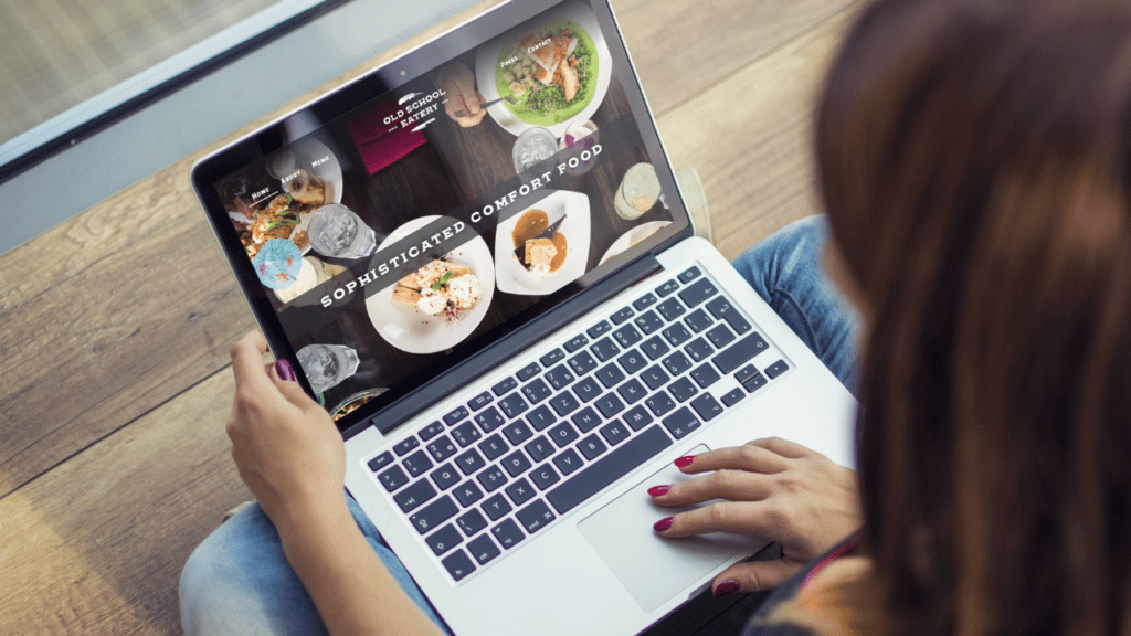 Laptop sitting open on a woman's lap with Old School Eatery website loaded